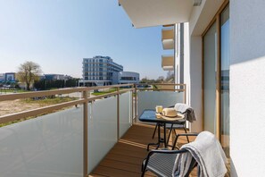 A balcony equipped with chairs and a table, offering a view of nearby buildings.