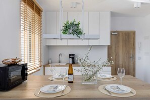 A compact kitchen with white cabinets, a wooden countertop, and a small dining table set for two.