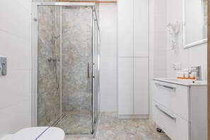 A sleek bathroom featuring a glass-enclosed shower, a modern sink, and white tiles.