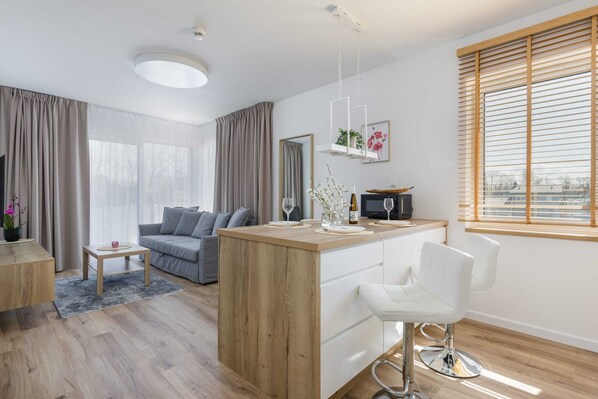 A cozy living room featuring a gray sofa, a coffee table, and large windows letting in natural light.