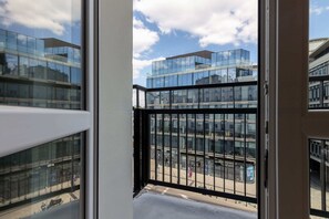 A balcony overlooking the city, with a view of urban buildings and bright skies.
