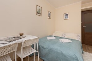 A bedroom with a comfortable double bed, soft blue bedding, and wicker chairs, offering a serene and relaxing atmosphere.

