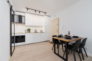 A compact kitchenette featuring white cabinetry, modern appliances, and minimalistic decor.