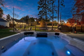 The photo doesn't do the size of this hot tub justice...COMFORTABLY fits 10! Look out onto the firepit, bbq deck and basketball court while relaxing