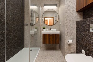 Stylish bathroom with a walk-in shower, mosaic tiles, and elegant fixtures, offering a luxurious feel.
