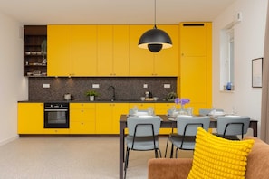 Fully equipped kitchen with vibrant yellow cabinets, a dining table, and modern appliances, ideal for meal preparation.