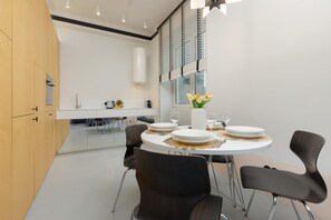 Modern dining area with a round table, sleek chairs, and elegant tableware, perfect for shared meals.
