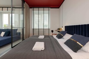Cozy bedroom with a dark headboard, soft bedding, and red ceiling accents, creating a comfortable space.
