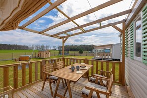 A well-furnished outdoor dining area under a wooden roof, perfect for enjoying meals with scenic surroundings.