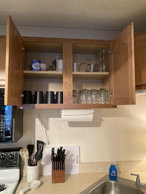 The kitchen is well-stocked with dishes, pots, pans, utensils and knives.