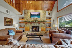 Gather around the large stone fireplace in the cozy living room with comfortable seating.