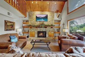 Gather around the large stone fireplace in the cozy living room with comfortable seating.