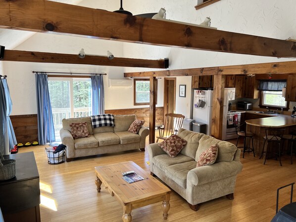 View of living area, kitchen with eat-in island and door to side deck and yard 
