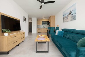 Comfortable living room with a large green corner sofa, TV, and open-plan space.
