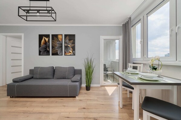 A stylish living room with a gray sofa, wooden coffee table, and modern decor, including vibrant wall art.