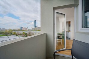 A balcony with a seating area, offering a serene view of the surrounding greenery and urban skyline.