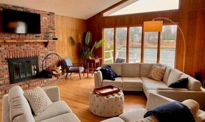 Spacious living room with ample seating, smart TV, fireplace, and a water view.