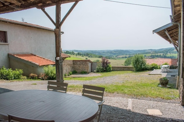 Gßte / Maison de vacances 'CÎté Cour' à VillechenÚve (RhÎne, Monts du Lyonnais, Ouest de Lyon, proximité de la Loire) : salon de jardin dans la cour privative avec capacité de 12 personnes à l'ombre.