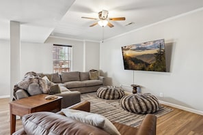 Relax and unwind in this open, spacious room with a sectional around a large TV.