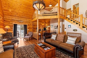 View of entire living room, loft area, dining room, and exit to back yard.