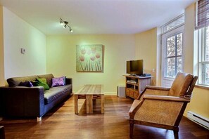 Living room with leather sofa bed and door to back balcony & original artwork