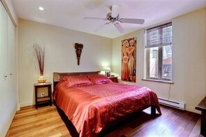 Bedroom with solid teak wood queen size bed, original artwork and hardwood floor