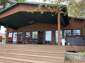 A covered deck with a hot tub, fan to stay cool, grill, & enough seating for all