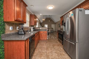 The kitchen is fully equipped with ample counter space, storage in cabinets, and a double-door refrigerator with a deep freezer for food storage.