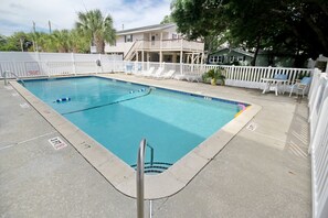 Large swimming pool with lounge chairs, tables, and chairs.