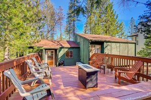 a deck with seating, a fire table, and string lights