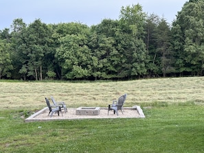 Fire pit area in the backyard that is stocked with wood