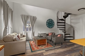 Living room w/seating and spiral staircase.