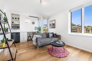 This light-filled living area offers stylish comfort with a plush sofa, vibrant decor, a breakfast bar, and access to a sunny balcony retreat