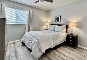 A queen bed with USB chargers in the headboard. A dresser, two closets and TV