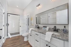 Large bathroom with tiled, walk-in shower, dual-sink vanity, full-size W/D