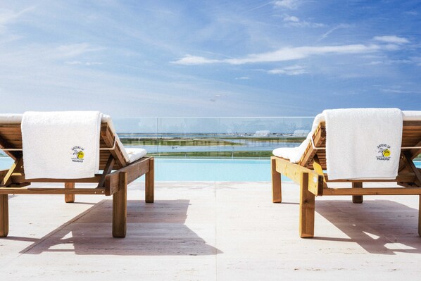 Infinity-Pool auf der Dachterrasse mit Liegestühlen und Sonnenschirmen