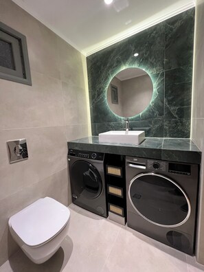 Wc next to the living room with washing machines and dryer.