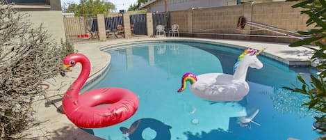 Swimming pool with pink flamingo and white unicorn inflatables