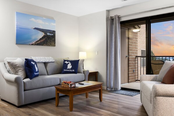 A unit featuring a comfortable sofa, complemented by a balcony offering a picturesque view of the lake.