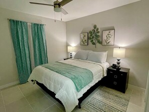 Queen size bedroom with two night stands and lamps. There is a phone charger clock on the right side