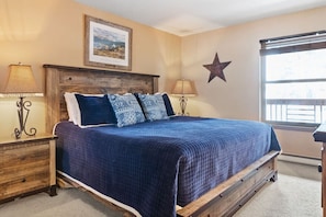 The cozy master bedroom boasts a king-size bed in a lovely bed frame, a 55” TV, and an attached full bathroom.