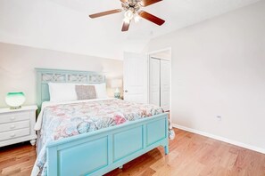 Bright bedroom with colorful sheets and ceiling fan