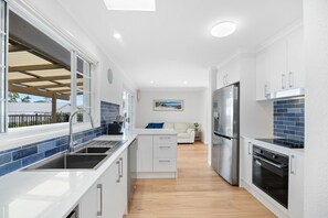 Galley kitchen with stove top, oven, microwave, dishwasher and nespresso machine