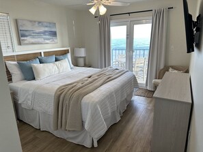 Primary bedroom featuring a king sized bed, dresser, and access to the balcony. 