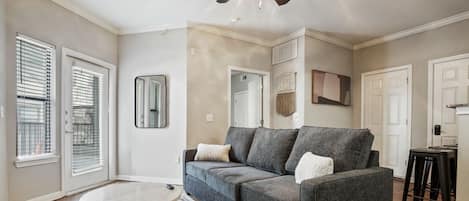 Open living room with sleeper sofa, smart tv, and balcony