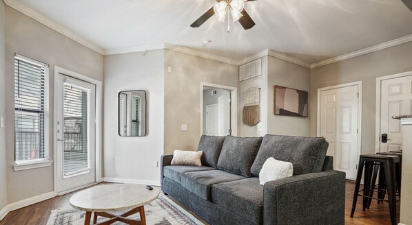 Open living room with sleeper sofa, smart tv, and balcony