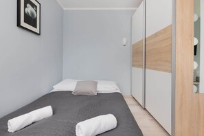 A bright bedroom with a double bed, soft gray bedding, and a mirrored wardrobe for a modern and minimalist look.
