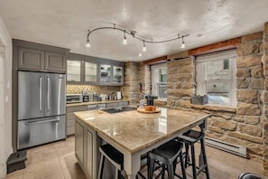 The lovely kitchen has everything you need to prepare a delicious meal at home with a spacious kitchen island, stainless steel appliances, and even a dual-sided fireplace providing a homey ambiance to the room!