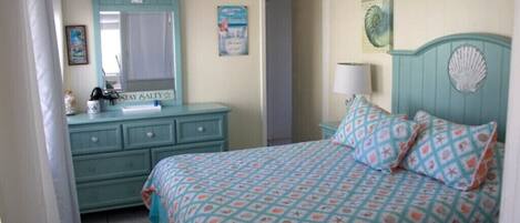 Bright beachy bedroom with a comfortable queen-sized bed and plenty of drawers 