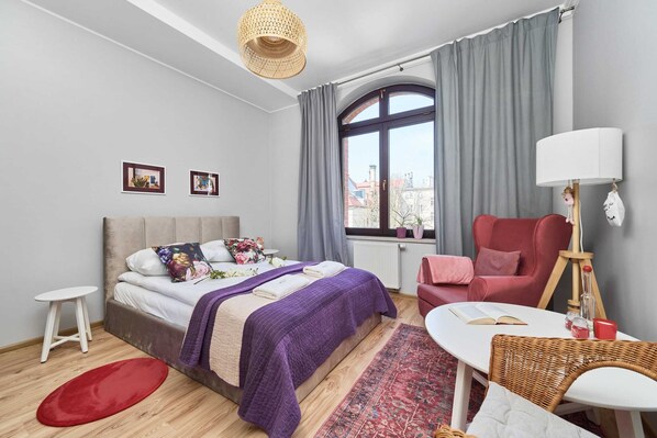 A cozy living room with a pink armchair, a large window, and stylish decor.
